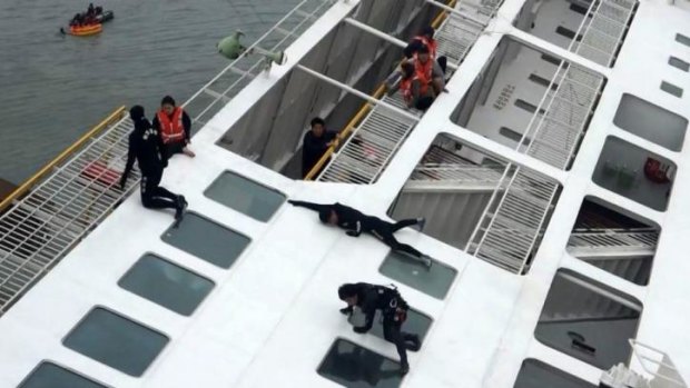 Maritime officers, in black, rescue passengers, in orange life vests, on Wednesday.