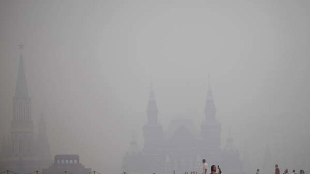 A tourist takes pictures at Red Square in a thick blanket of smog.