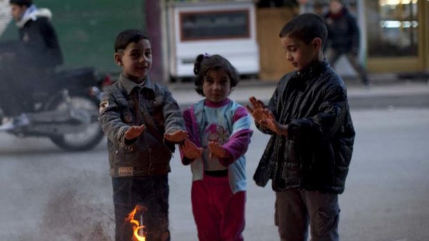 Syrian children warm their hands by a fire ... in other areas of the stricken city of Homs, witnesses warn of mass executions.