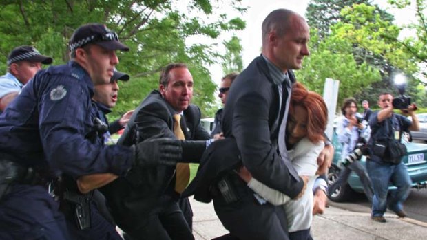 Prime Minister Julia Gillard is dragged away by her close protection team.