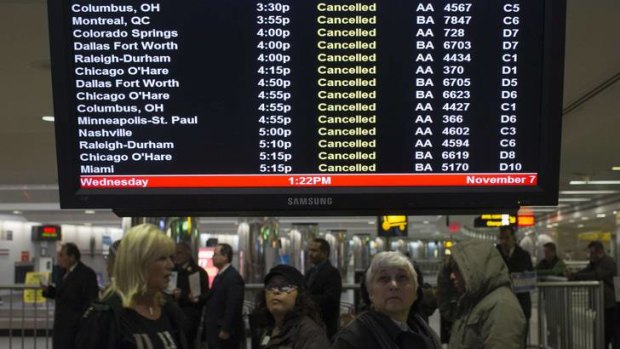 Travellers look at a monitor displaying cancelled flights at LaGuardia on Wednesday.
