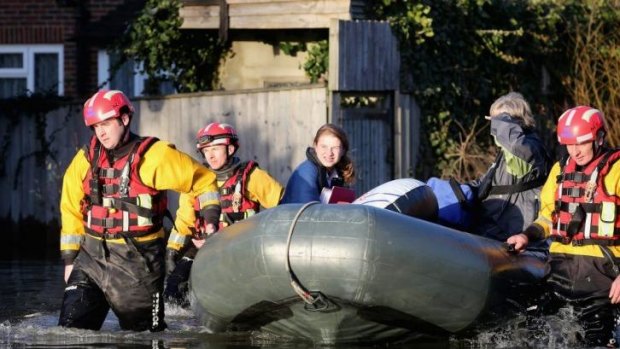 Lending a hand: A woman is evacuated from her home by police in Chertsey. The Environment Agency continues to issue severe flood warnings for a number of areas on the river Thames in the commuter belt west of London.