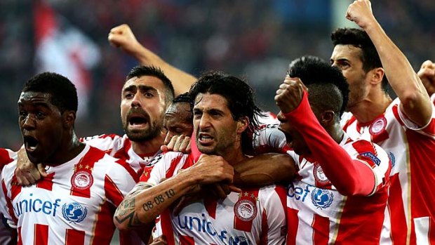 Olympiakos' midfielder Alejandro Dominguez (centre) celebrates with teammates after scoring a goal during the match against Manchester United in Athens on Tuesday.