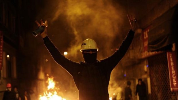 A protester flashes victory signs as he faces riot police during a demonstration in Istanbul. 