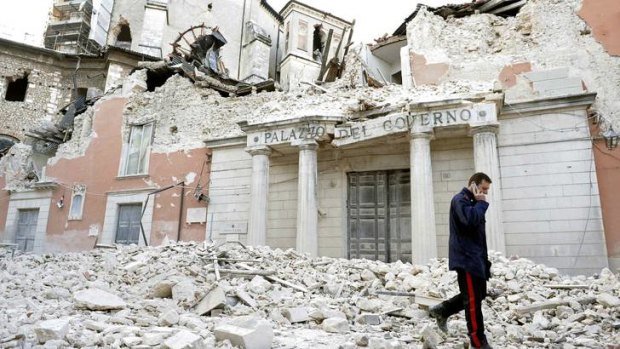 An Italian military carabinieri walks on debris past destroyed buildings after an earthquake, in downtown Aquila.