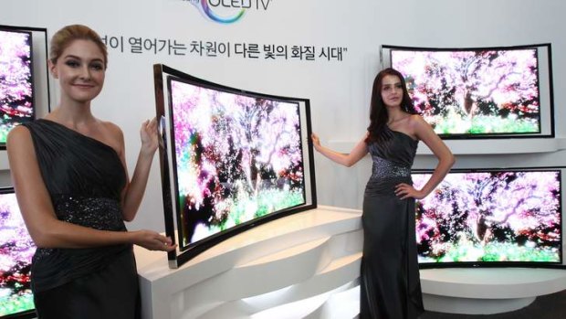Models pose with Samsung's 55-inch curved OLED TV during a press conference.