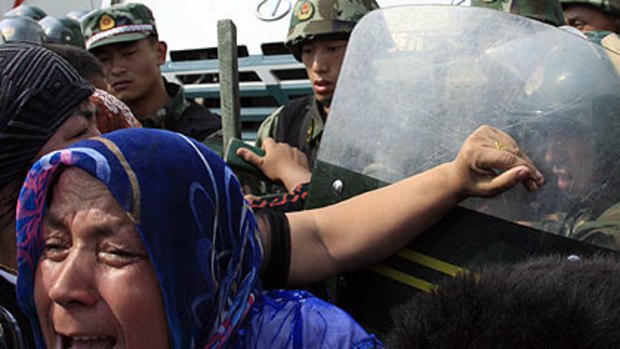 Fury ... a woman shoves Chinese soldiers in riot gear as angry locals confront authorities in Urungi. "Release our husbands, free our sons," they chanted.
