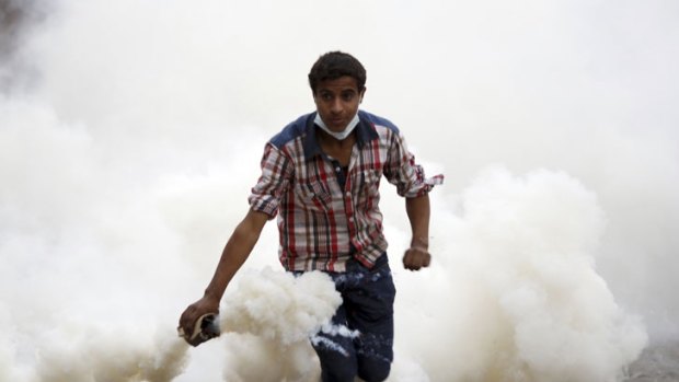 A protester prepares to throw back a tear gas canister, thrown earlier by police during clashes near Tahrir Square in Cairo.