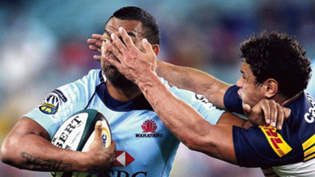 Facial... Waratahs fullback Kurtley Beale feels the full force of a Brumbies defender at ANZ Stadium on Saturday night. NSW won the Super 14 match 19-12.