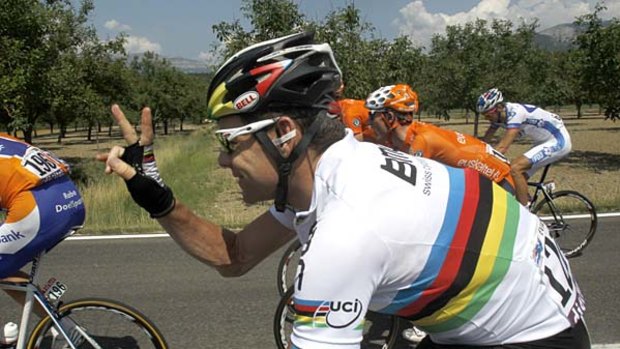 Cadel Evans of Australia flashes a v-sign as he rides in the peloton.