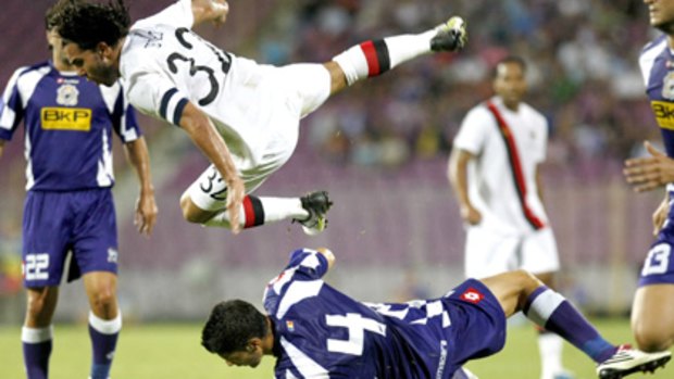 Manchester City's Carlos Tevez is heavily challenged by FC Timisoara's Luchin.