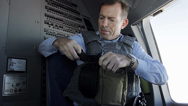 Buckle up: The Prime Minister prepares his body armour as he flies to a recognition ceremony in Tarin Kowt in Afghanistan in October.