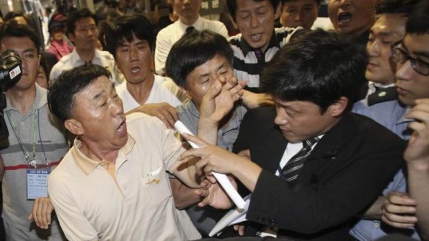 Emotions high ... Family members of passengers aboard the sunken ferry Sewol struggle with a security officer (right), while attempting to attend the trial of 15 Sewol ferry crew members at Gwangju District Court.