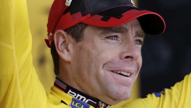 Cadel Evans smiles on the podium with the leader's yellow jersey.