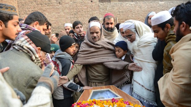 Pakistani mourners gather around a coffin during the funeral ceremony for victims of an attack by Taliban militants at an army-run school.