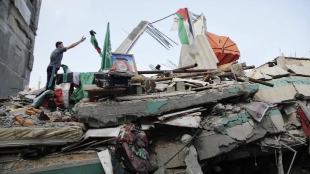 A man throws a flag atop the rubble of the home of Hamas Gaza leader Ismail Haniyeh.