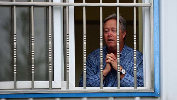 Praying for release: Chip Starnes stands behind a barred window at his Beijing medical supplies factory, after being held hostage for five days.