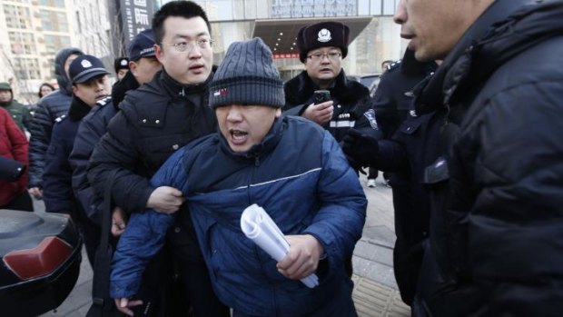 Chaotic scenes: A plain-clothes policeman escorts Zhang Qingfang, the lawyer of Xu Zhiyong, to a police car.
