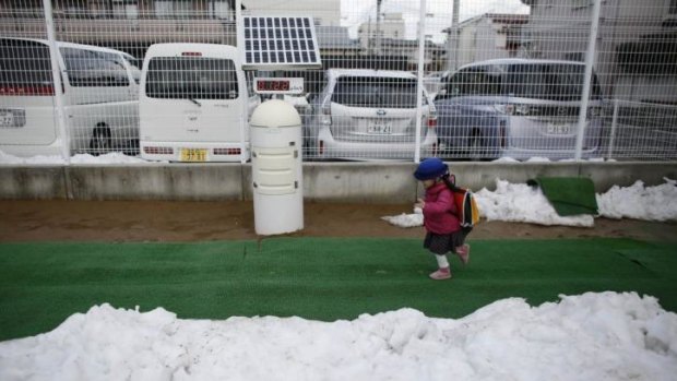 A girl runs past a geiger counter on her arrival at the Emporium Kindergarten in Koriyama.