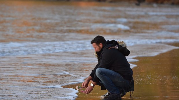 Jason Ruszczyk, Justine Damond's brother,  places a flower into the water at Freshwater Beach during a vigil for his sister. 