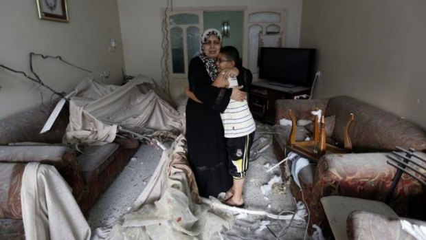A Palestinian woman hugs her son at their damaged living room after a neighboring building was targeted in an Israeli military strike in Gaza.