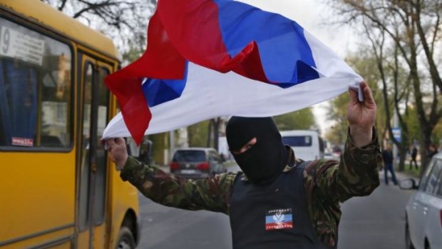 Defying Ukraine's new government ... A masked pro-Russia protester waves the Russian flag in Donetsk, eastern Ukraine.