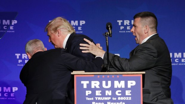 Members of the Secret Service rush Republican presidential candidate Donald Trump off the stage.