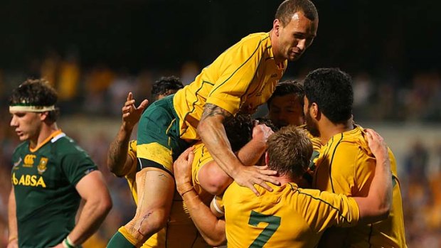 Jump for joy ... Quade Cooper joins fellow teammates to embrace Scott Higginbotham after his try brought the Wallabies back on par with the Springboks.
