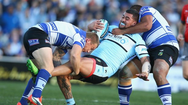 In the spotlight: Andrew Fifita is tackled by two Bulldogs players on Sunday.
