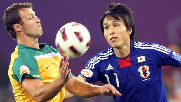 Australia's Lucas Neill fights for the ball against Japan's Ryoichi Maeda.