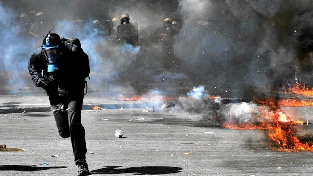 A protester runs from riot police during a 24-hours general strike in Athens.