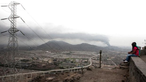 Blanketing the hills districts: People watch as smoke spreads from a fire in downtown Lima.