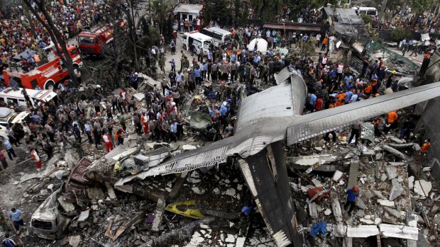 Security forces and rescue teams examine the wreckage of an Indonesian military C-130 Hercules transport plane.