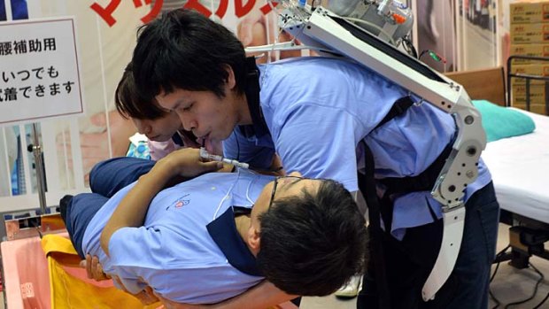 Extra lift: A Japanese man wearing the "Muscle Suit" powered by compressed air stored in an air tank on his back, lifts a fellow worker during a demonstration at the annual International Robot Exhibition in Tokyo.