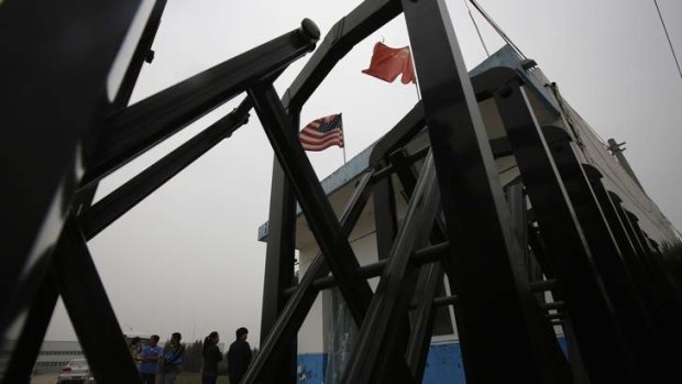 Flags belonging to the U.S. and China flutter through a closed gate at a factory where Chip Starnes, the co-owner, is being held hostage, on the outskirts of Beijing, June 25, 2013.