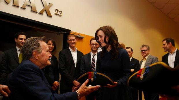 Former President George H.W. Bush, left, receives a tri-corner hat from actress Heather Lind, right, at a private screening in Houston, Texas. 