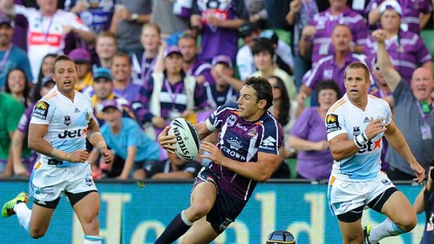 Billy Slater evades Gold Coast tacklers to become the Storm's greatest try-scorer yesterday.