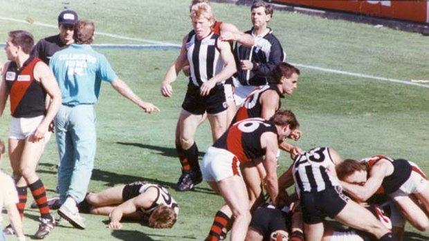 At quarter-time in the 1990 grand final, Collingwood's Gavin Brown is on the ground after being knocked out by Bomber Terry Daniher amid an all-in brawl.