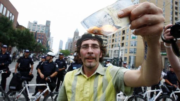 A man burns a Canadian five-dollar note during a protest at the G20 summit in Toronto.