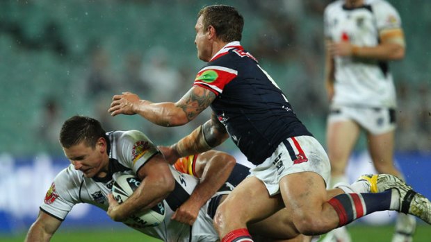 Jacob Lillyman of the Warriors is tackled by the Roosters' defence.