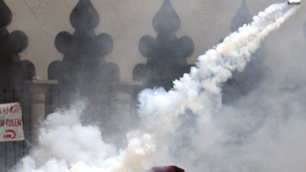 A protester throws back a tear gas canister fired by Malaysian police during a demonstration in Kuala Lumpur.