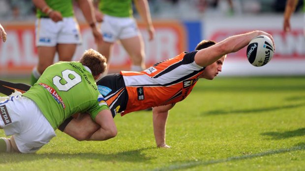 Wests Tigers' Simon Dywer plants a try despite the best efforts of Glen Buttriss of the Raiders.