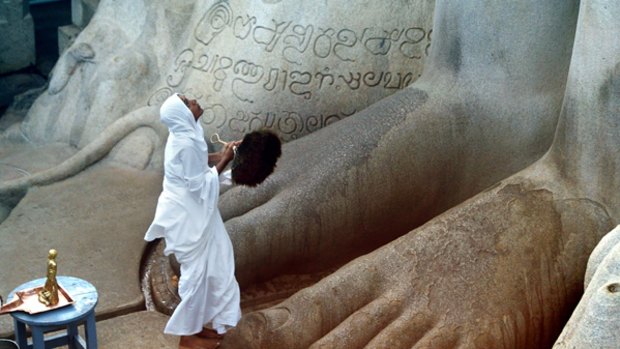 Piety prevails ... a Jain pilgrim prays at the feet of the statue of Gommateshwara.