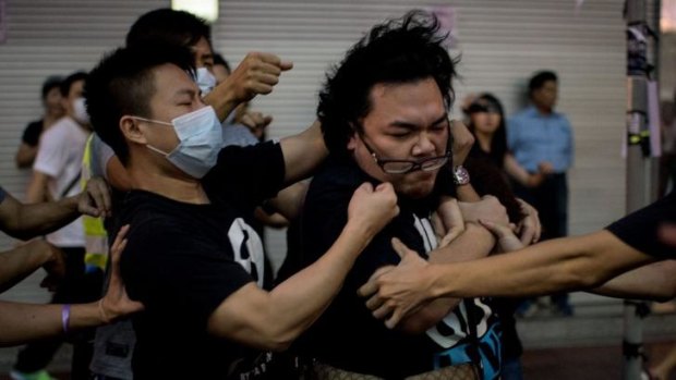 A group of men in masks rough up a man who tried to stop them from removing barricades from a pro-democracy protest area in the Causeway Bay district of Hong Kong.