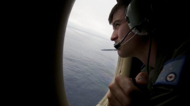 Needle in a haystack ... A crewman of an RAAF AP-3C Orion aircraft looks out his observation window whilst searching for missing Malaysia Airlines Flight MH370 over the Indian Ocean.