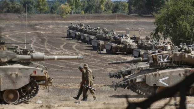 Israeli soldiers walk past tanks near the border with the Gaza Strip.