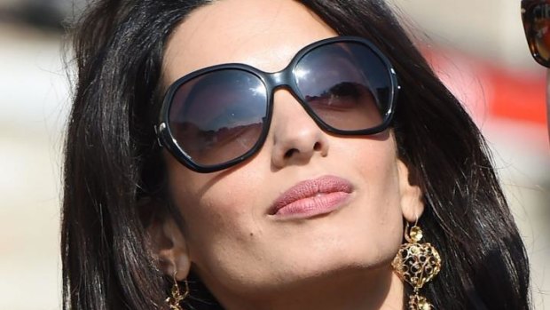 Amal's Dolce and Gabbana gold earrings and Prada sunglasses.