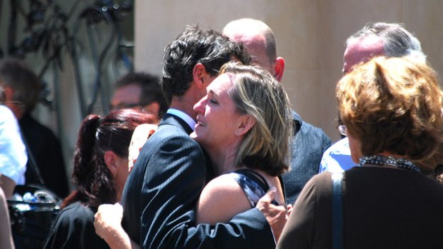 Harley Cuzens is consoled by a friend outside the memorial service for his two young daughters.