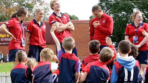 Demons footballers Jack Watts (left) and Brad Green answer questions about the club ending their association with sponsor Energy Watch from a group of children at the Melbourne Football Club school holiday super clinic at Junction Oval.