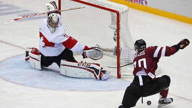 Latvia's Miks Indrasis (R) attempts a shot on Canada's goalie Carey Price.